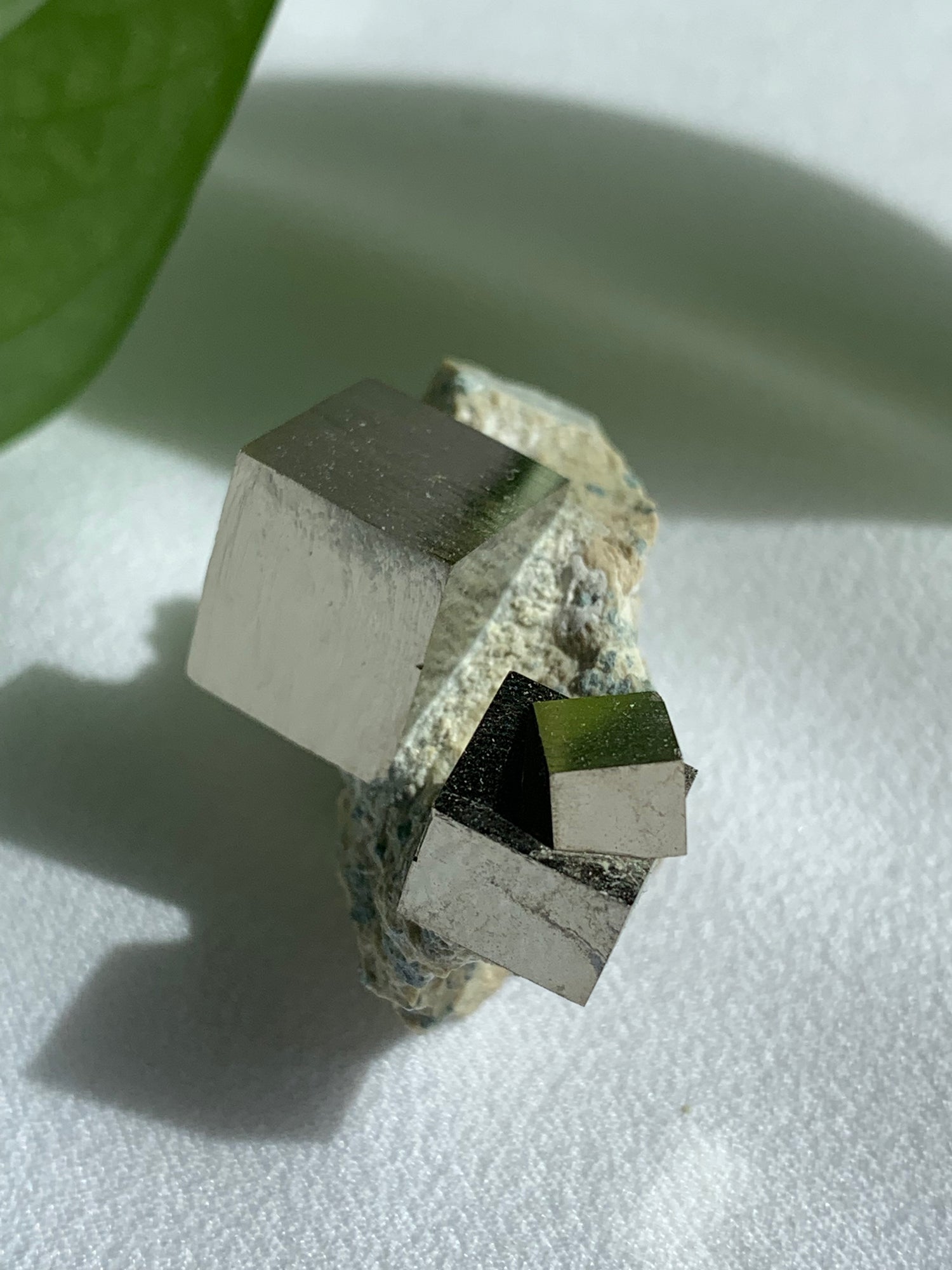 Golden, mirror like cubes of crystal pyrite on a soft marl matrix. One large stand alone cube protrudes from the matrix, a secondary cube has a inter grown cube within it.